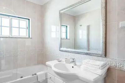a white bathroom with a sink and a mirror at Villa Minerva in Albufeira