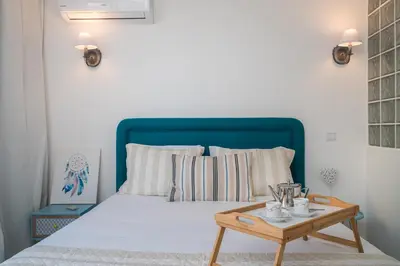 a bed with a blue headboard and a wooden table at Serenity by the Marina, Vilamoura in Quarteira