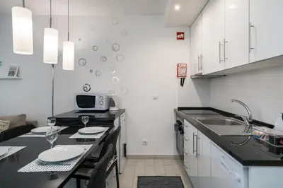a kitchen with white cabinets and a black counter top at Serenity by the Marina, Vilamoura in Quarteira