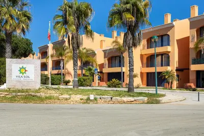a building with palm trees in front of it at AL - Apartamento Vila Sol F5 E in Vilamoura