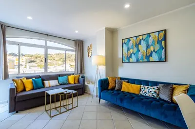 a living room with a blue couch and yellow pillows at Top renoviertes Apartment mit großer Terrasse in Albufeira