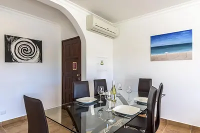 a dining room with a glass table and black chairs at FLH Albufeira Vila Mira Flat with Pool in Albufeira