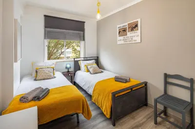 a bedroom with two beds and a chair in it at Kwadalayo Art Quarters in Faro