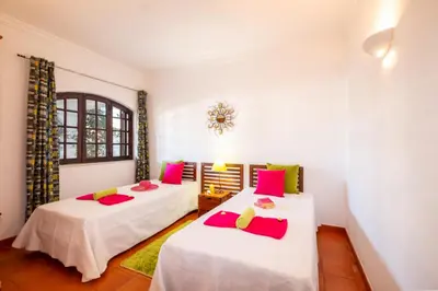 two beds in a room with white walls and pink pillows at Villa Atlas by Algarve Vacation in Albufeira