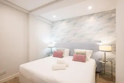 a white bedroom with a large white bed with two lamps at Marina Design T1 in Albufeira