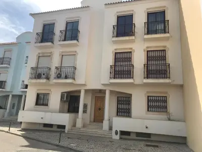 a white building with balconies and a door at Vila Columbus T2 Frente Mar e Piscina in Quarteira