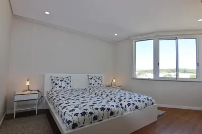 a white bedroom with a bed and a window at Amendoeiras II - Central Vilamoura in Vilamoura