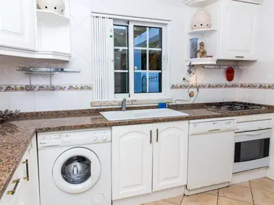 a white kitchen with a washing machine and a sink at Joia da Galé House by Stay ici Algarve Holiday Rental in Albufeira