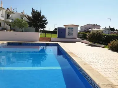 a blue swimming pool in front of a building at Joia da Galé House by Stay ici Algarve Holiday Rental in Albufeira