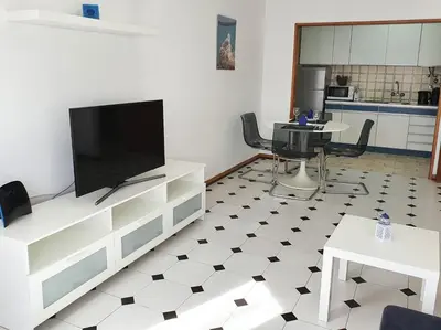 a living room with a flat screen tv and a kitchen at Solaris- Familiar, Wifi, Totalmente Equipado in Quarteira
