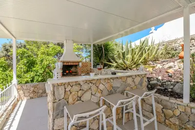 a patio with a stone bar with stools and a fireplace at Villa Redonda in Loulé