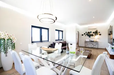 a dining room and living room with a glass table and white chairs at Villa Redonda in Loulé