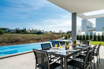 a dining table and chairs on the patio of a house at Colinas do Golfe Vilamoura Sun by SAPvillas in Vilamoura