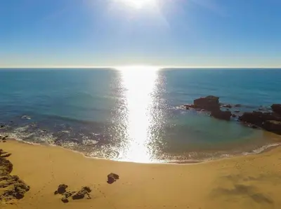 a beach with the sun shining on the water at Apartment Aveiros Beach- D´Alma Amado in Albufeira