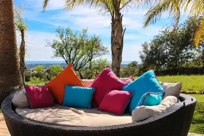 a wicker couch with colorful pillows on a patio at Elegant Villa in Loulé with Private Pool in Loulé