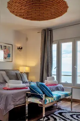 a bedroom with two beds and a couch and a window at Villa Front de Mer avec Piscine Jacuzzi Accès Privé Plage en famille et entre amis in Albufeira