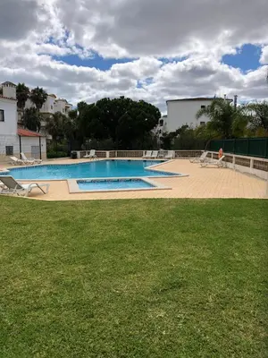 a large swimming pool with a person sitting on a lawn at Albufeira Emblematica Apartment - Wifi & Pool in Albufeira