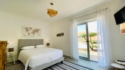 a white bedroom with a bed and a large window at Otto by Check-in Portugal in Quarteira
