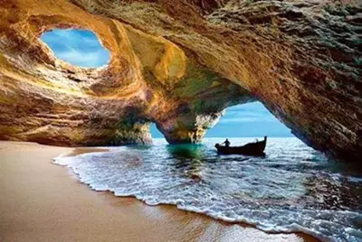 a boat in the water under a cave on the beach at Bright apartment with sea view in Albufeira - 62 m², Pool in Albufeira