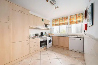 a kitchen with wooden cabinets and a washer and dryer at Casa Maya - Vale do Garrão in Quinta do Lago