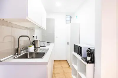 a white kitchen with a sink and a microwave at Faro Downtown Ria Formosa I in Faro