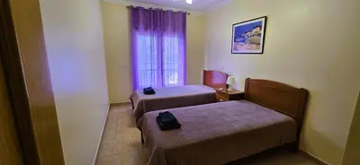 a small room with two beds and a window at Odete Túnel - Albufeira in Albufeira