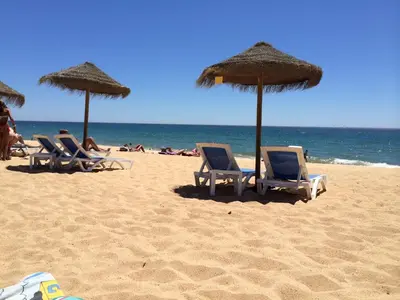 a group of chairs and umbrellas on a beach at CosyAvenida Mar, 2 rooms in Quarteira
