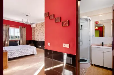 a room with a red wall with a bed and a bathroom at Villa Calipso in Albufeira