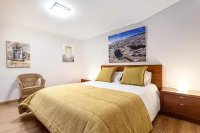 a bedroom with a large bed and a chair at Villa Simone by Intiholidays in Quarteira