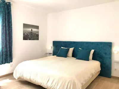 a bed with a blue headboard and two pillows at Albufeira + appartement proche plage avec piscine in Albufeira