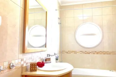 a bathroom with a sink and a mirror and a tub at Albufeira l AMAZING terrasse with jacuzzi Encosta da Orada in Albufeira