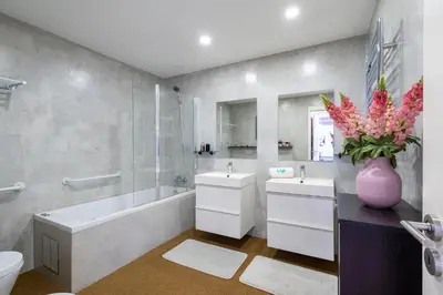 a bathroom with two sinks and a tub and a vase of flowers at Marina Luxor in Vilamoura