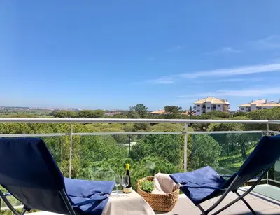 two chairs and a table with a bottle of wine on a balcony at Falesia beach l roof top pool in Albufeira