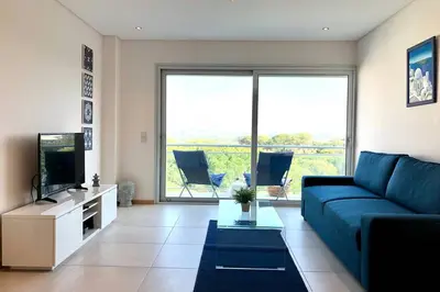a living room with a blue couch and a tv at Falesia beach l roof top pool in Albufeira