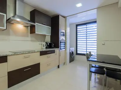 a kitchen with wooden cabinets and a table with chairs at V4, Villa Jardins Branqueira3 near Beach, Albufeira in Albufeira