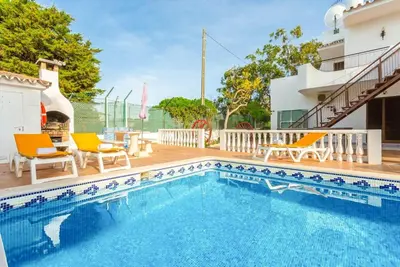 a swimming pool with two chairs and a house at VILLA COELHO in Albufeira