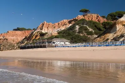 a beach with blue chairs and a mountain at Pool and Garden Village-near beach in Albufeira