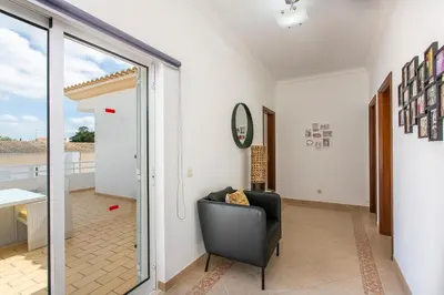 a living room with a chair and a sliding glass door at Villas Mar e Brisa in Albufeira