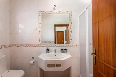 a white bathroom with a sink and a mirror at Villas Mar e Brisa in Albufeira