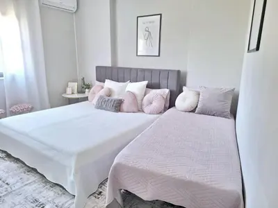 a white bedroom with a large bed with pink pillows at Feliz Algarve in Albufeira
