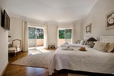 a bedroom with a large white bed and a television at Villa Mayfair - Quinta do Lago in Almancil