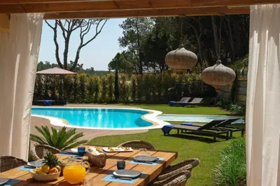a patio with a table and a swimming pool at Villa Mayfair - Quinta do Lago in Almancil