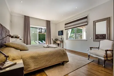 a bedroom with a bed and a chair and windows at Villa Mayfair - Quinta do Lago in Almancil