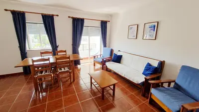a living room with a table and blue chairs at Apartamento Carvalhal in Quarteira