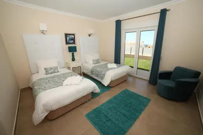 a bedroom with two beds and a chair and a window at Casa Coralea in Guia