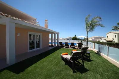 a patio with chairs and a table on the grass at Casa Coralea in Guia