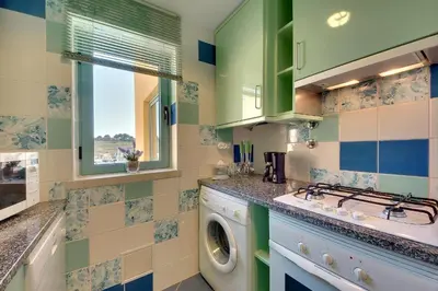 a laundry room with a washing machine and a window at Marina Sand Residence in Albufeira
