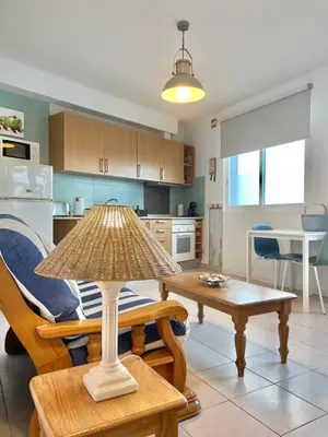 a living room with a table and chairs and a kitchen at Bayview Apartment 106 in Albufeira