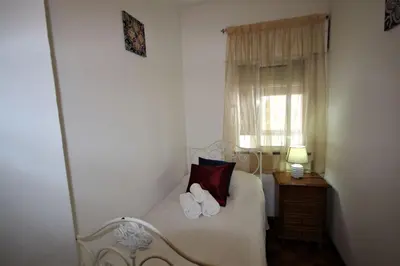 a bedroom with a white bed with a window at Apartamento Brás in Quarteira