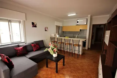 a living room with a couch and a kitchen at Apartamento Brás in Quarteira